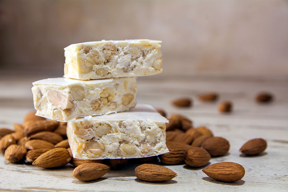 Italian festive torrone or nougat and almonds on a rustic wooden table, copy space, close up with selected focus, very narrow depth of field